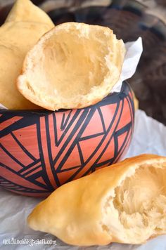 two pieces of bread sitting in a bowl next to each other on top of wax paper