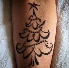 a woman's leg with a christmas tree tattoo on it