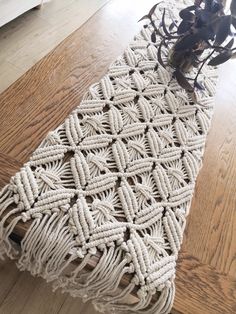 a table runner made out of rope on top of a wooden floor next to a potted plant