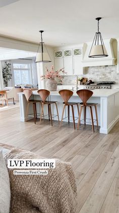 a kitchen with white cabinets and wooden chairs next to an island in the middle of it