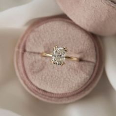 an engagement ring sitting on top of a pink velvet box with a diamond in it