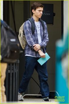 a young man with a backpack and blue folders is walking out of a building