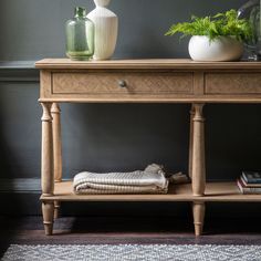 a wooden table with two vases and a towel on it next to a rug