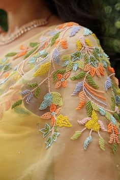 the back of a woman's yellow dress with colorful flowers on it