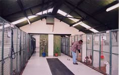 a man is standing in an enclosed area with his dog and other animals on the floor