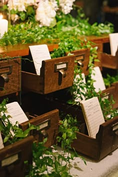 several wooden boxes with notes attached to them sitting on the ground in front of flowers