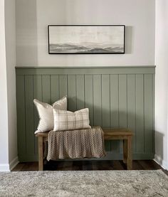 a wooden bench sitting in the corner of a room next to a painting on the wall