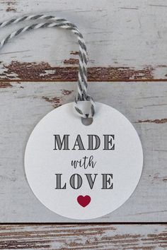 a white tag that says made with love hanging from a rope on a wooden surface