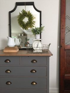 a dresser with a mirror and wreath on top