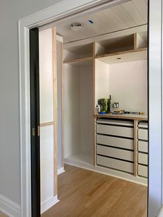 an empty kitchen with white walls and wooden floors, is seen through the open door