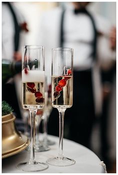 two champagne flutes with strawberries in them sitting on a table next to each other