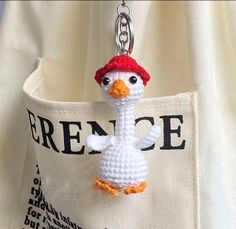 a crocheted keychain with a white bird wearing a red hat