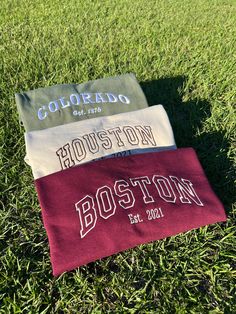 three towels laying on top of a lush green grass covered field next to each other