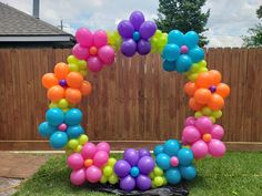 an arch made out of balloons in the shape of a flower is shown on grass