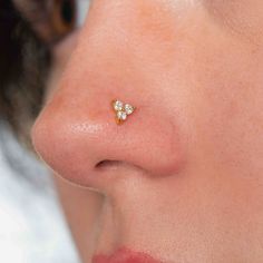 a woman's nose with two small white flowers on the side of her nose