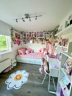 a room with a bed, desk and shelves filled with pictures on the wall next to a window