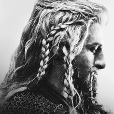 a black and white photo of a man with long hair, braids on his face