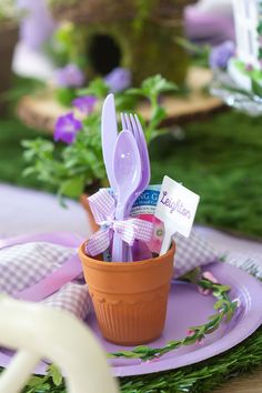 there is a small cup with forks and spoons in it on the purple plate