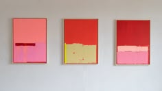 three paintings are hanging on the wall next to each other, one is pink and yellow