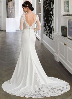 a woman in a white wedding dress is looking into the mirror