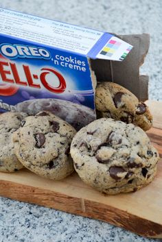 chocolate chip cookies are on a cutting board next to a box of oreo cookies