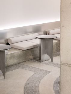 two tables sitting next to each other in a room with white walls and concrete flooring