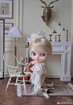 a doll sitting on top of a wooden floor next to a white chair and table