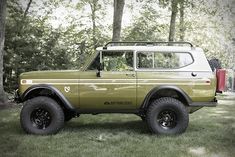 an old green truck parked in the grass