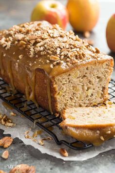 a loaf of bread sitting on top of a cooling rack next to some apples and nuts