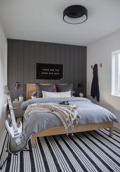 a bed room with a neatly made bed and a guitar on the wall next to it