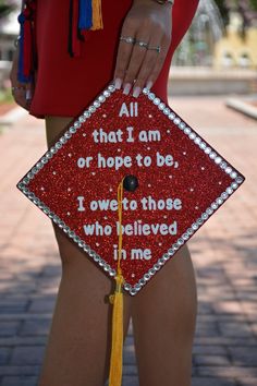 a woman holding a red graduation cap with words on it