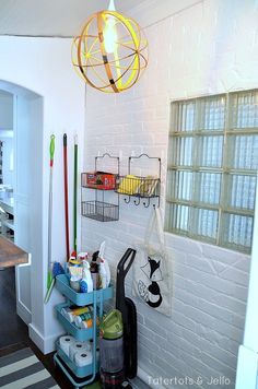 a white brick wall with several shelves and baskets on it, hanging from the ceiling