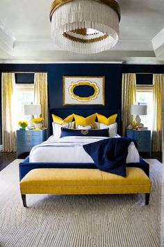 a bedroom with blue walls, yellow and white bedding and chandelier above the bed