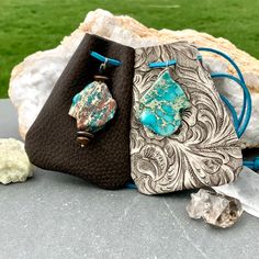 two purses sitting on top of a table next to some rocks and crystals in the grass