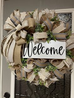 a welcome sign hanging on the front door of a house decorated with burlocks and ribbons