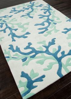 a rug with blue and green trees on it in the middle of a wooden floor