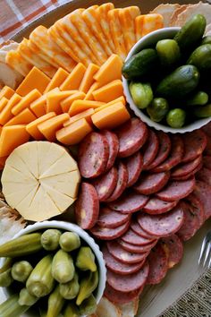 a platter filled with different types of cheeses, meats and olives