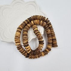 two bracelets made out of wood beads on a white plate next to a napkin