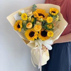 a woman is holding a bouquet of sunflowers