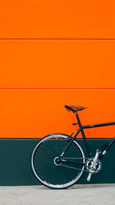 a black bike leaning against an orange wall