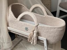 a white wicker baby bassinet with tassels on the handles and sides