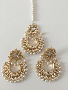 "Gorgeous kundan chand baali earrings and matching tikka. The tikka has a pearl string . The earrings and tikka have meena work at the back. Made from a silver alloy with gold plating.  Only tikka or only earrings available too Tikka and earrings: 2.8\" long and 2.1\" at widest" Chand Bali Earrings, Chand Bali, Jewellery Kundan, Earrings Kundan, Maang Tika, White Pearl Jewelry, Indian Jewelry Earrings, Bali Earrings, Indian Jewellery Design Earrings