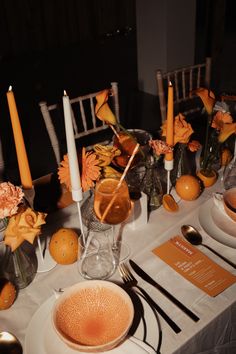 the table is set with orange flowers and candles