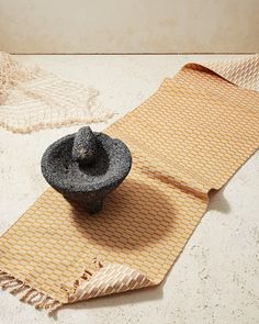 a black hat sitting on top of a mat next to a bowl and rugs