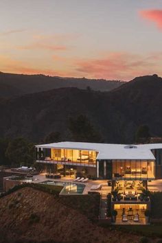 an aerial view of a modern house at dusk with mountains in the backgroud