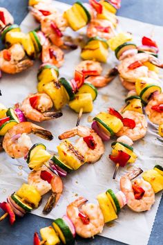 several skewers of vegetables and shrimp on a sheet of paper