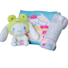 a stuffed animal sitting next to a pillow on top of a white surface with an image of a cake and cupcake