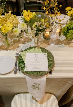 the table is set with yellow flowers and place settings for two people to sit at