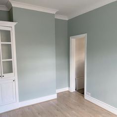 an empty room with blue walls and white trim on the door, hardwood flooring