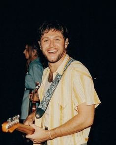 a man with a guitar smiling at the camera